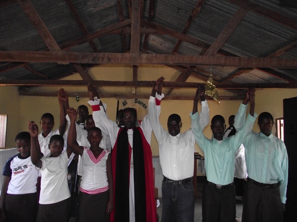 Bishop Mwita raising hands with those he confirmed. ''Go forth and serve the Lord\"