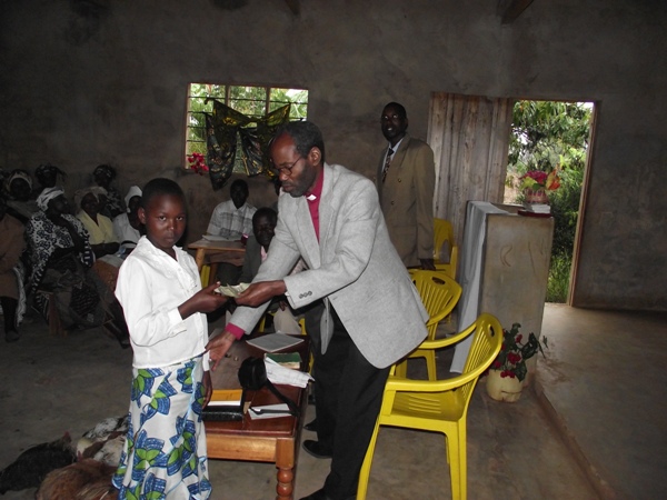 A little girl donating money during a fundraising for music instruments at Kitagasembe church near the border with Kenya