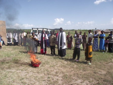 Bishop Mwita and the congregation witnessing the burning of witchcraft tools and charms surrendered by the Meng'anyi family